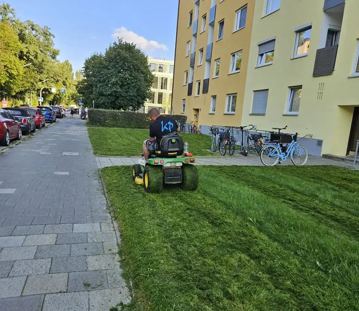 Hausmeisterservice in München beim Rasenmähen vor einem Wohngebäude